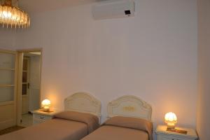 莱萨L'Antico Borgo的一间卧室配有两张床,墙上有两盏灯