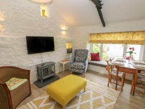 滕比Primrose Cottage的客厅配有电视和带椅子的桌子