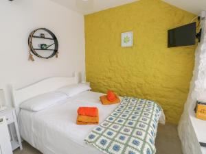 滕比Primrose Cottage的卧室配有白色床和橙色枕头。