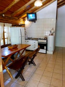 波特雷里约斯Cabañas Troncos Del Salto的厨房配有木桌和冰箱。