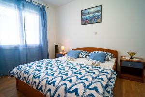 尼亚卢卡Sunny的一间卧室配有一张带蓝色和白色棉被的床