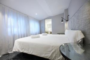 马德里U-Sense Madrid Santa Ana的卧室配有一张白色大床和一张玻璃桌