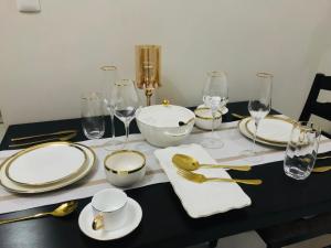 马尼拉BGC Uptown 1 BR Condo的一张黑桌,上面有白色的板子和金色的餐具
