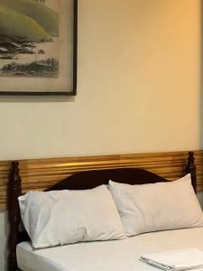 TagumInside Room Inn的一张带木制床头板和白色枕头的床