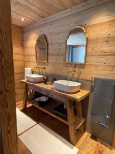 GsteigAlpen Charme - Chalet d'Hôtes et SPA的木墙上带两个水槽的浴室