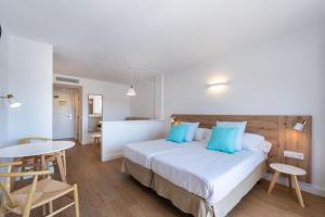 卡拉博纳Aparthotel Ferrer Lime Isabel的一间卧室配有一张带蓝色枕头的床和一张桌子