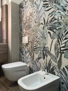 圣欧费米亚拉默齐亚B&BUrszula Gizzeria Lido的浴室设有白色卫生间和植物壁纸。