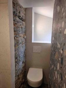 科尔特Appartement au cœur de la ville的浴室配有白色卫生间和石墙。