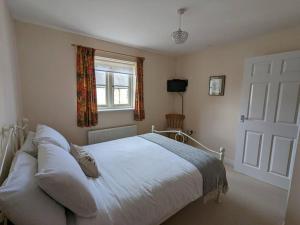 泰特伯里Cosy coach house in historical Tetbury的卧室配有白色的床和窗户。