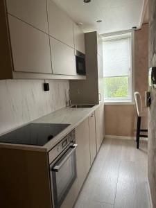卑尔根MK8 Apartment的厨房配有白色橱柜、水槽和窗户。