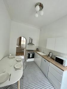 尼姆Appartemment Nimes Arènes的白色的厨房配有桌子和水槽