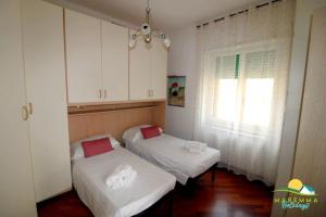 福洛尼卡Maremma Holidays : Fiore Apartment的配有白色橱柜和窗户的客房内的两张床