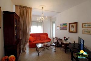 福洛尼卡Maremma Holidays : Fiore Apartment的客厅配有红色的沙发和桌子