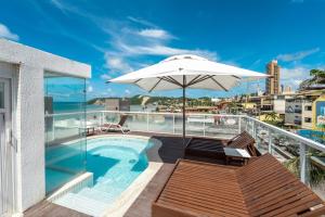 纳塔尔DELUX PRAIA Flats的阳台设有游泳池和遮阳伞。