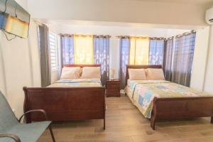 罗索VJ's Guesthouse Vacation Home, Jimmit, Dominica的配有窗户和一张四柱床的客房内的两张床