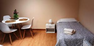 阿尔苏阿Castelao Apartments的小房间设有一张床和一张桌子及椅子