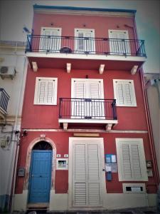 墨西拿Vecchia Paradiso - A un passo dal Mare的红色的建筑,设有两扇蓝色的门和阳台