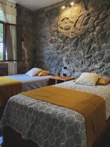 巴克里索莫雷诺港Hostal Pimampiro的石墙客房的两张床