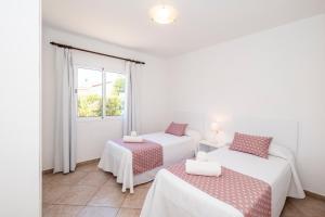 休达德亚格山度假屋的白色客房的两张床,设有窗户