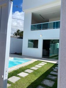 卡马萨里Casa Completa com piscina, 800m da praia de Jauá的一座白色的房子,前面设有一个游泳池