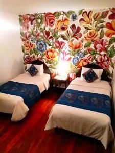 库斯科Casona Dorada Hotel Cusco的客房设有两张带花卉图案壁纸的床。