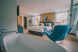 拉夏贝尔德邦达Terra-Beka Lodge的一间卧室配有一张床、一张蓝色椅子和一个浴缸