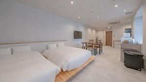 高山Relax Hotel Takayama Station的白色卧室配有两张床和一张桌子