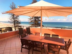 库鲁姆海滩库拉姆海滩度假酒店的海滩上的一张木桌、椅子和遮阳伞