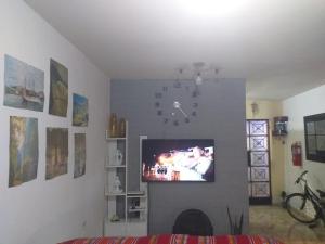 利马Chakana Family Home Lima Airport的客厅设有时钟,墙上设有电视