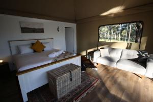 波高尔宾Two Fat Blokes Outback Adventure Glamping的一间卧室配有一张床、一张沙发和一把椅子
