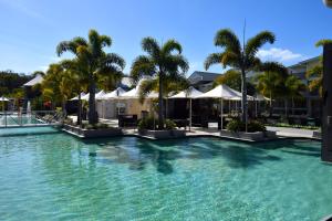 阿格奈什沃特1770 Lagoons Central Apartment Resort Official的一座棕榈树和遮阳伞的大型游泳池