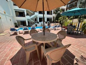 巴亚尔塔港Vallarta Sun Suites的庭院里配有桌椅和遮阳伞