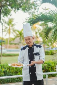 坦噶Tanga Beach Resort & Spa的一位戴着厨师帽的男孩,拿着一盘食物