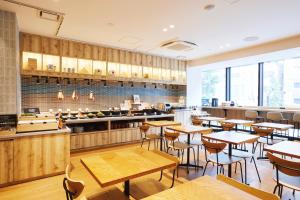 东京hotel MONday Akihabara Asakusabashi的餐厅设有木桌、椅子和柜台