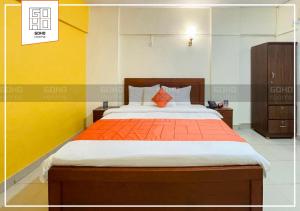 卡拉奇GOHO Rooms 10th Commercial的一间卧室配有一张带橙色毯子的大床