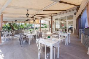 萨索斯Chrisa Hotel的庭院里的餐厅配有白色的桌椅