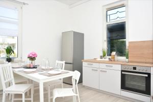 科堡CO03-HI Apartment in Coburg的白色的厨房配有白色的桌子和椅子
