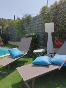阿格德MimiLou rez-de-jardin avec piscine & spa的两把带蓝色枕头的躺椅,位于游泳池旁