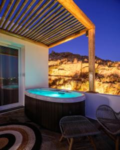 米克诺斯城Vrachos Suites Mykonos的天井上的热水浴池配有2把椅子