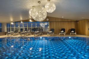 慕尼黑玛丽蒂姆慕尼黑酒店的酒店大堂设有游泳池、椅子和吊灯