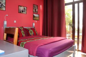 基加利Umusambi B&B的红色卧室配有床和桌子