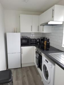 伦敦Delight Apartment, Close to Excel, London City Airport & O2!的厨房配有白色橱柜和洗衣机。