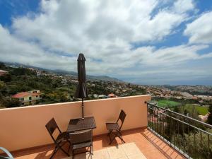 丰沙尔Costa Residence Funchal View的阳台配有桌椅和遮阳伞。