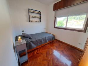 尼格兰Playa América, Nigrán, dúplex.的一间卧室配有一张床,铺有木地板