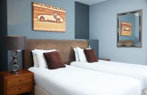 奇切斯特Trents by Greene King Inns的两张位于酒店客房的床,墙上有一辆汽车