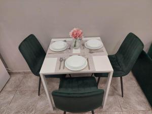 依克希亚Emerald home的一张桌子上摆放着绿色椅子和盘子,鲜花盛开