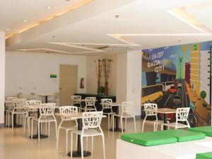 马尼拉Go Hotels North EDSA的一间设有白色桌椅的用餐室和一个保龄球馆