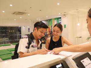 马尼拉Go Hotels Timog的男人和女人在柜台上写文章