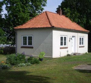 BardowickFerienhaus Strobel的一座白色的小房子,拥有橙色的屋顶