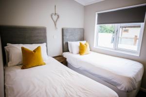 布莱克浦Ream Hills Holiday Park的带窗户的客房内的两张床,配有黄色枕头